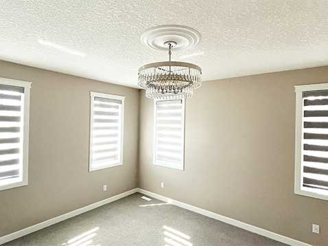 Empty room with four windows and a chandelier